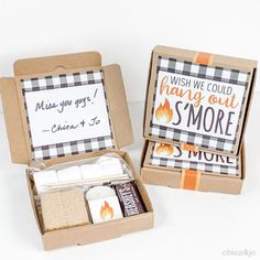 two small boxes with marshmallows and other treats in them sitting on a table