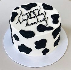 a birthday cake decorated with black and white cow print icing, on a plate