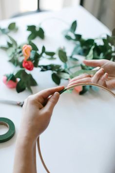 two hands are working on a flower arrangement