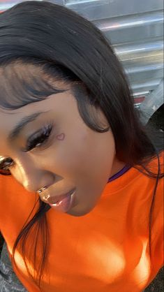 a woman with piercings on her nose wearing an orange shirt