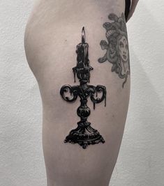 a black and white photo of a candle on the back of a woman's thigh