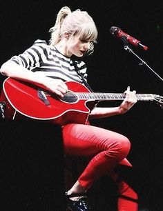 a woman sitting on top of a stool playing a red guitar and singing into a microphone