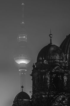 black and white photograph of two large buildings with lights on the top one building is lit up at night