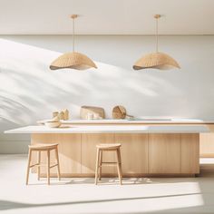 two wooden stools sit in front of an island with white countertops and light wood cabinets