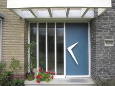 a blue door with a white arrow sign on the side and flowers in pots next to it