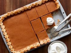 there is a cake that has been cut into squares and served with whipped cream on the side