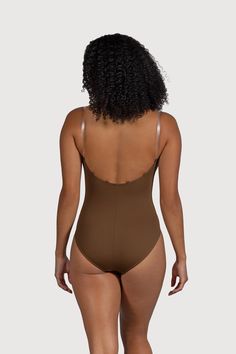 a woman in a brown bodysuit with her back turned to the camera, looking down