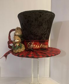 a black and red hat with a teddy bear on it's side sitting on top of a glass stand