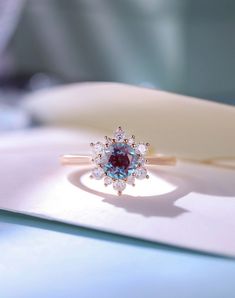 a close up of a diamond ring on a white plate with blue and red stones