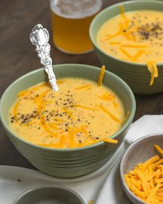 two bowls of soup with cheese on top and a spoon in the bowl next to it