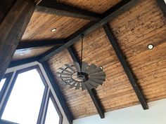 a large clock hanging from the ceiling in a room with wooden walls and beams on it