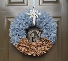 a wreath with a star on top and a nativity scene hanging from the front door