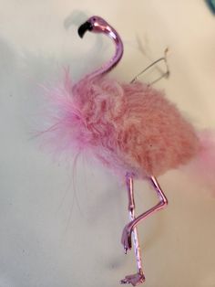 a pink flamingo keychain hanging on a white surface with some metal hooks attached to it