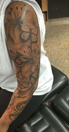 a man with a tattoo on his arm and some flowers in front of him is sitting down