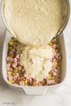 a white dish filled with potatoes, ham and gravy