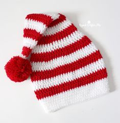 a red and white knitted hat with a pom - pom