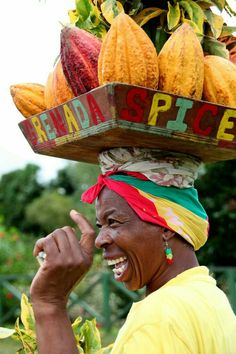 a woman wearing a basket on her head with fruit on it's top and smiling