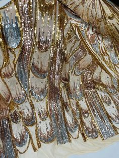 gold and silver sequins are on the back of a dress with long sleeves