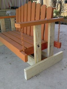 a wooden swing with chains attached to it on the concrete flooring in front of a building