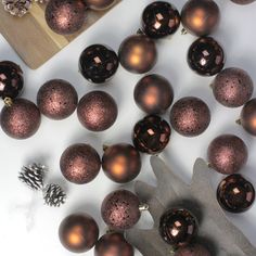 a bunch of brown christmas balls sitting on top of a white table next to a cutting board