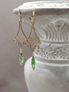 These vintage inspired earrings feature Art Deco style brass connectors and peridot green vintage glass beads. I love the intricate details and arabesque design of the brass connectors. They are lightweight yet sturdy, and extremely comfortable to wear. These long dangle earrings measure 2 1/2 inches long and hang from brass lever back ear wires. Perfect for a modern flapper look or a unique August birthday gift ABOUT THIS COLLECTION The sophisticated style of the Roaring Twenties is timeless. T Green Art Deco Drop Earrings, Art Deco Green Jewelry For Pierced Ears, Green Filigree Earrings For Formal Occasions, Green Formal Filigree Earrings, Green Filigree Drop Earrings, Green Brass Jewelry For Formal Occasions, Formal Green Filigree Earrings, Green Filigree Teardrop Earrings, Green Teardrop Filigree Earrings