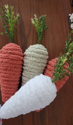 three crocheted carrots sitting on top of a wooden table next to each other