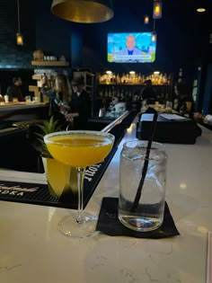 two drinks sitting on top of a bar next to each other