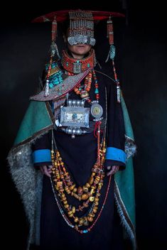 a man dressed in an elaborately decorated outfit and headdress, holding a camera