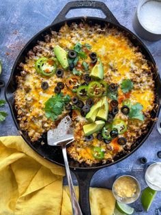 a skillet filled with mexican food and garnished with avocado