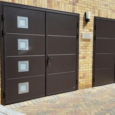 two brown garage doors with white windows on the side of a brick building