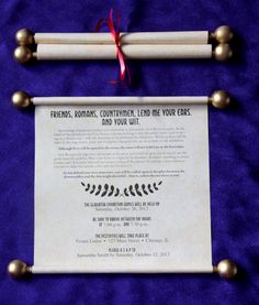 a scroll and two wooden poles on a purple cloth with a red ribbon tied around it