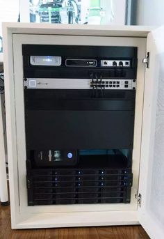 a white cabinet with several different types of electronic equipment in it on a wooden floor