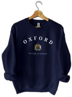 the oxford university sweatshirt is hanging on a wooden hanger, and it says oxford