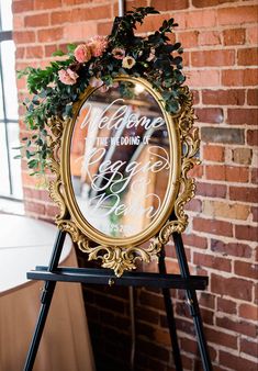 a gold framed mirror that says welcome to the bride and groom with flowers on it