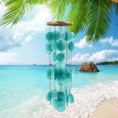 a wind chime hanging from the side of a palm tree on top of a beach