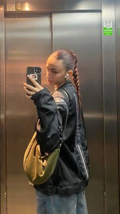 a woman taking a selfie with her cell phone in front of an elevator door