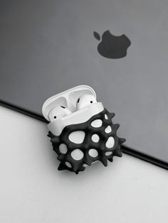 an iphone holder made out of black and white spiky material on top of a laptop