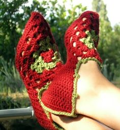 someone is wearing red crocheted slippers with green trim