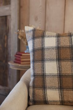 a plaid pillow sitting on top of a white couch next to a table with books