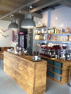 the inside of a coffee shop with lots of counter space and hanging lights above it