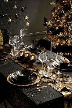 a table set for christmas with gold and black decorations