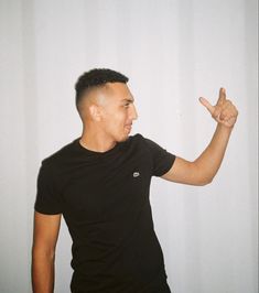 a man in black shirt pointing at something with one hand and the other holding his finger up