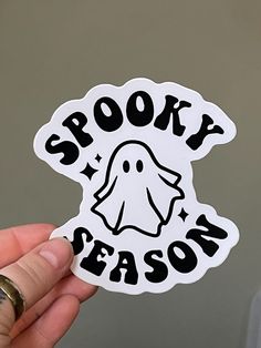 someone holding up a sticker that says spooky season