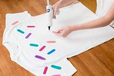 a woman is making a t - shirt with colored sprinkles on it