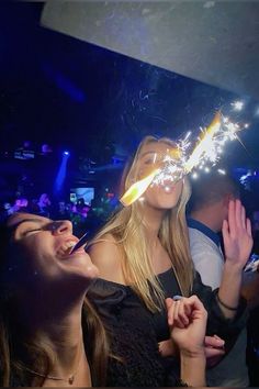 two girls are blowing out sparklers in the air