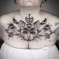 a woman with tattoos on her chest has three cats and a cross in the middle