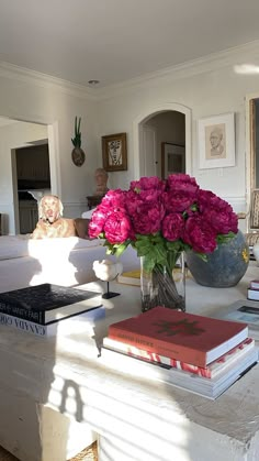 a vase filled with pink flowers sitting on top of a table next to two books