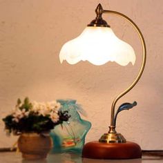 a table lamp sitting on top of a counter next to a vase with flowers in it