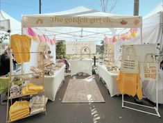 an outdoor market area with tables and chairs under a white tent that says the golden grt co