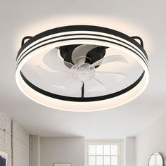 a white ceiling fan sitting on top of a light fixture in a living room next to a window